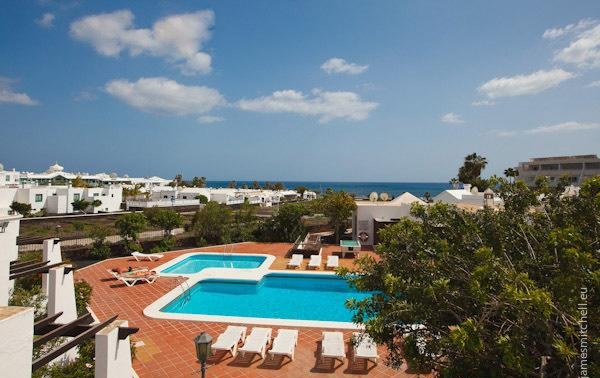Vista de las piscinas de Salmarina Bungalows con el mar al fondo